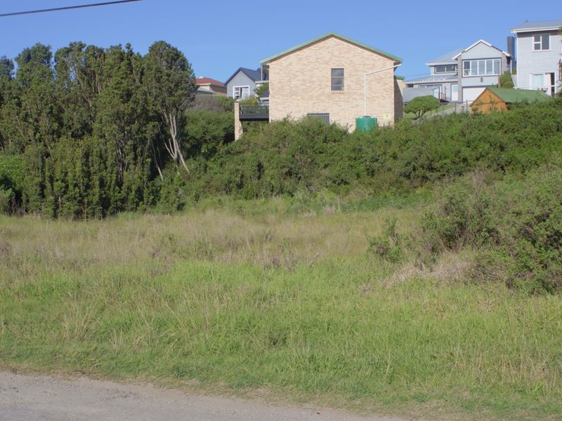 A view of a vacant residential plot of land with natural vegetation, situated in a developed neighborhood.
