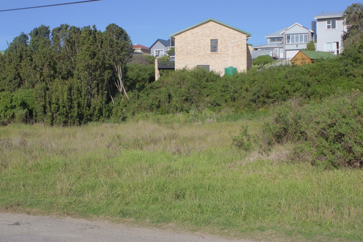 A view of a vacant residential plot of land with natural vegetation, situated in a developed neighborhood.