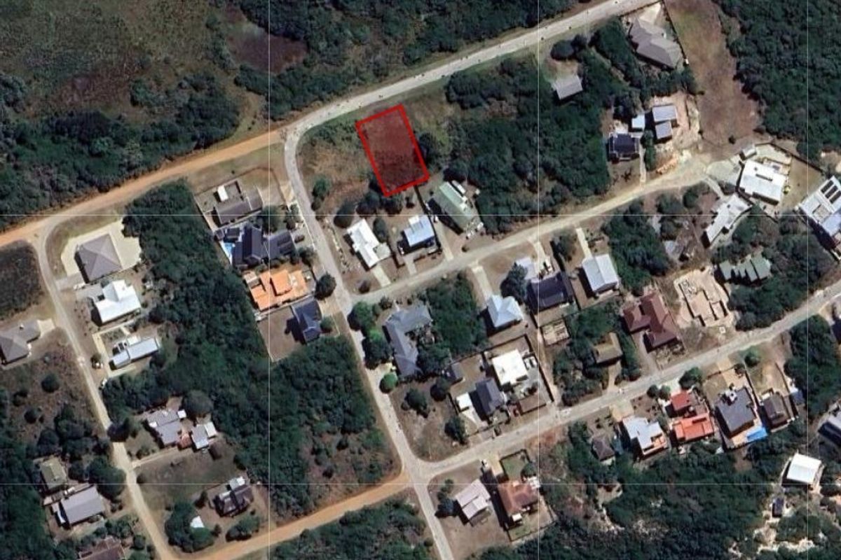 Aerial view of a vacant residential land plot highlighted in red, situated within an established neighborhood with surrounding vegetation and road access.