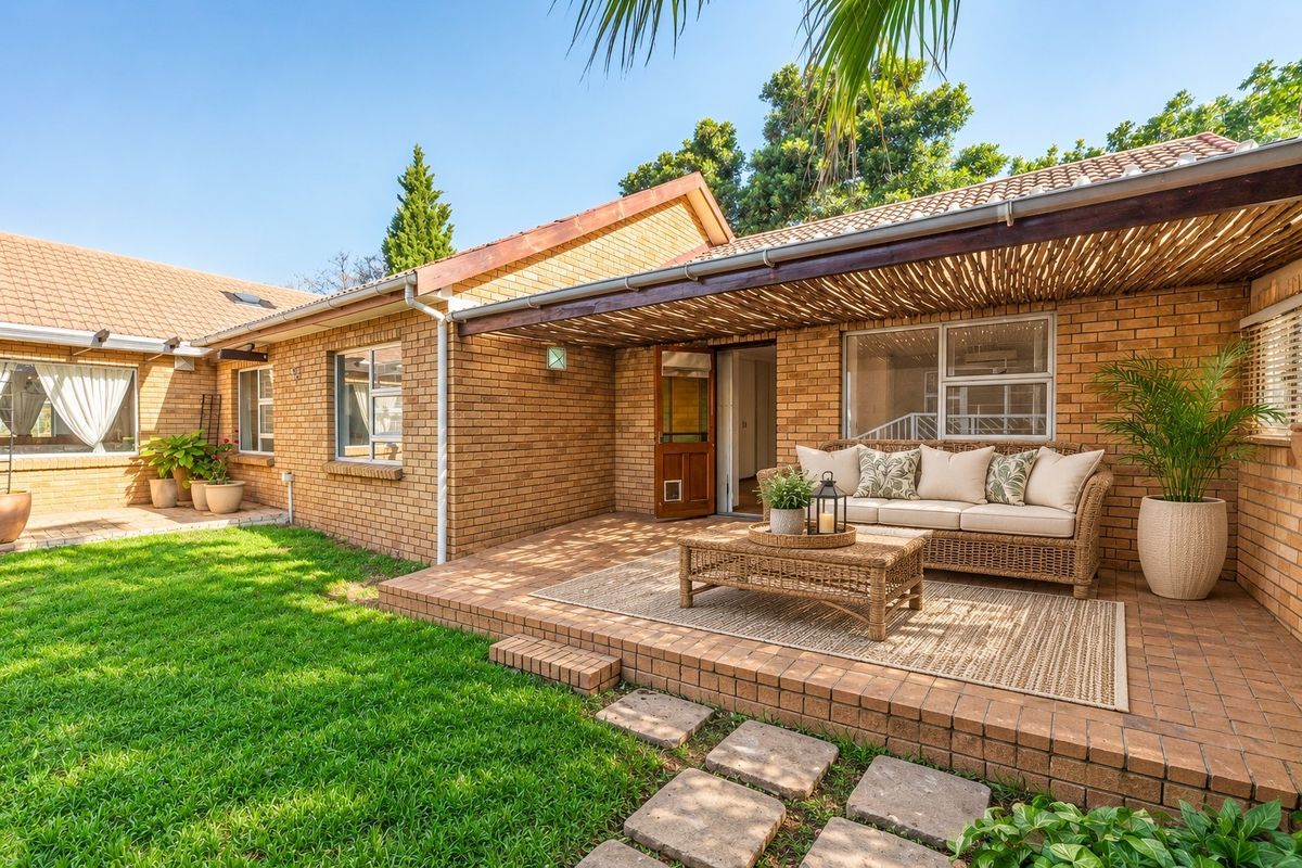 A well-maintained rear exterior featuring a brick facade, a covered patio with a timber pergola, and a neat garden with a lawn and stepping stones.