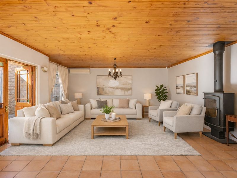 Spacious living room featuring a warm wood-paneled ceiling, tiled flooring, and a cozy freestanding fireplace, with direct access to the outdoor area.
