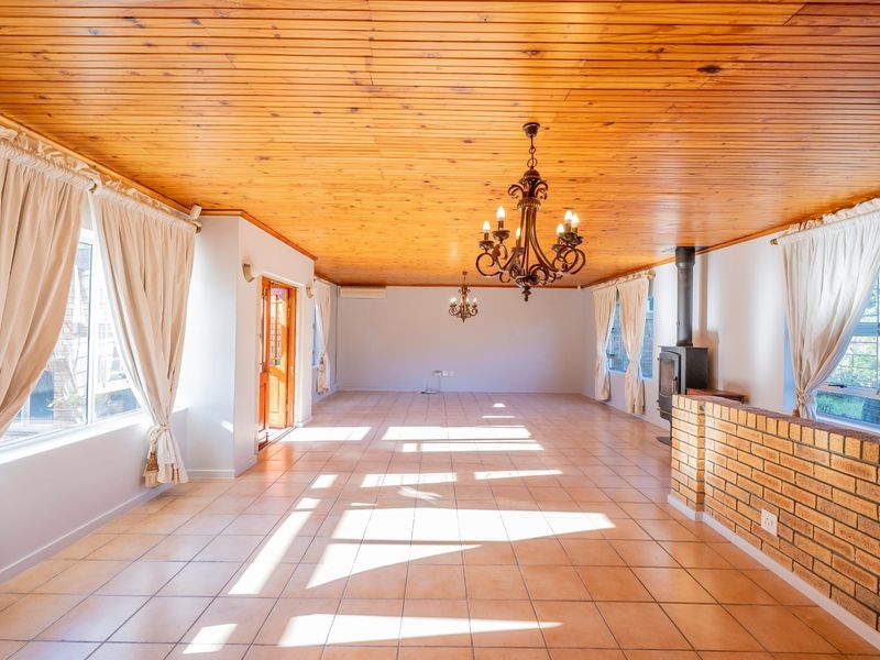 Spacious living area featuring a timber-clad ceiling, tiled flooring, and a built-in fireplace, offering a versatile and bright open-plan layout.