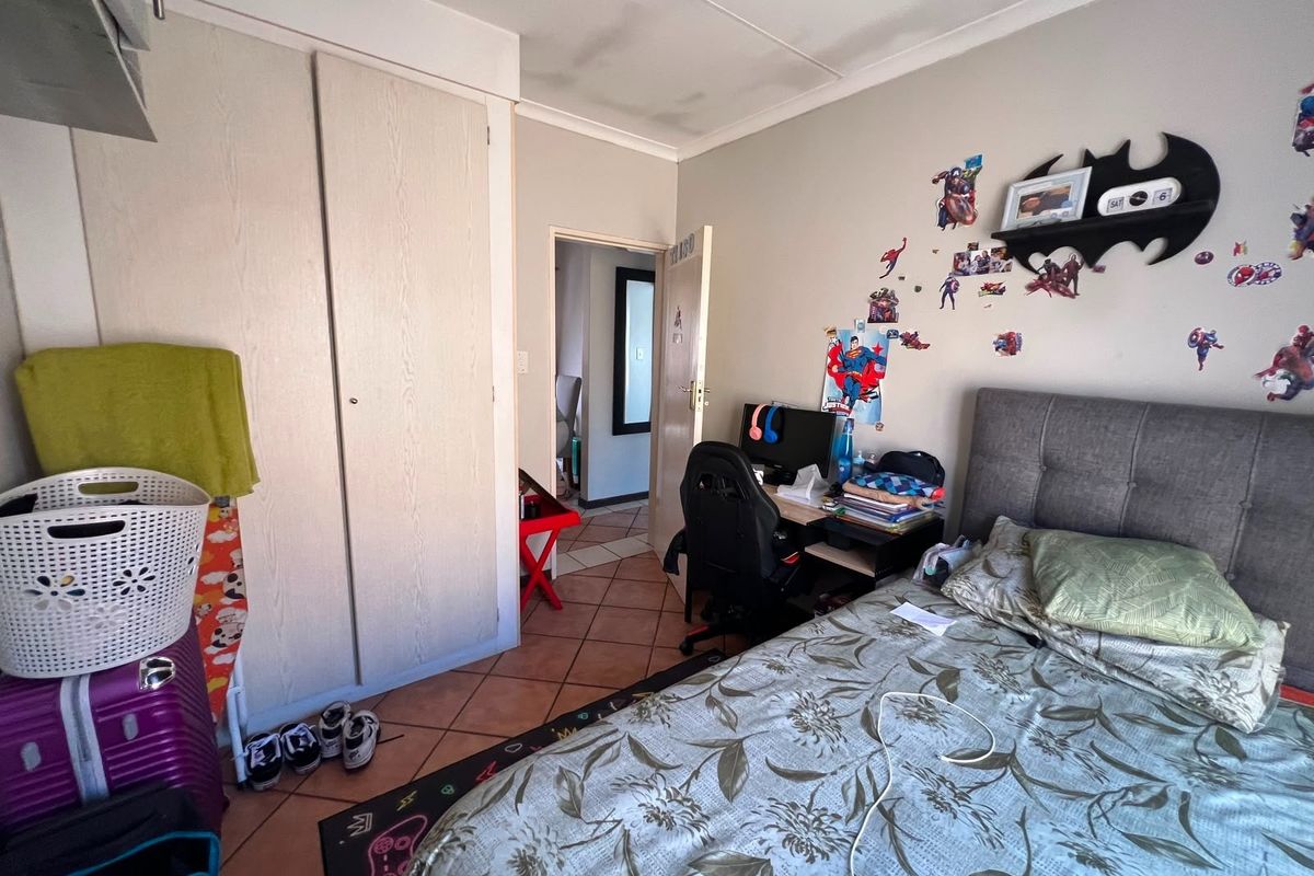 A bedroom featuring tiled flooring, a built-in wardrobe, and visible ceiling water staining, requiring maintenance and cosmetic updates.