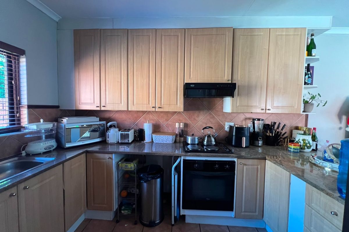 A functional kitchen featuring light wood-finish cabinetry, granite countertops, a tiled backsplash, and integrated cooking appliances.
