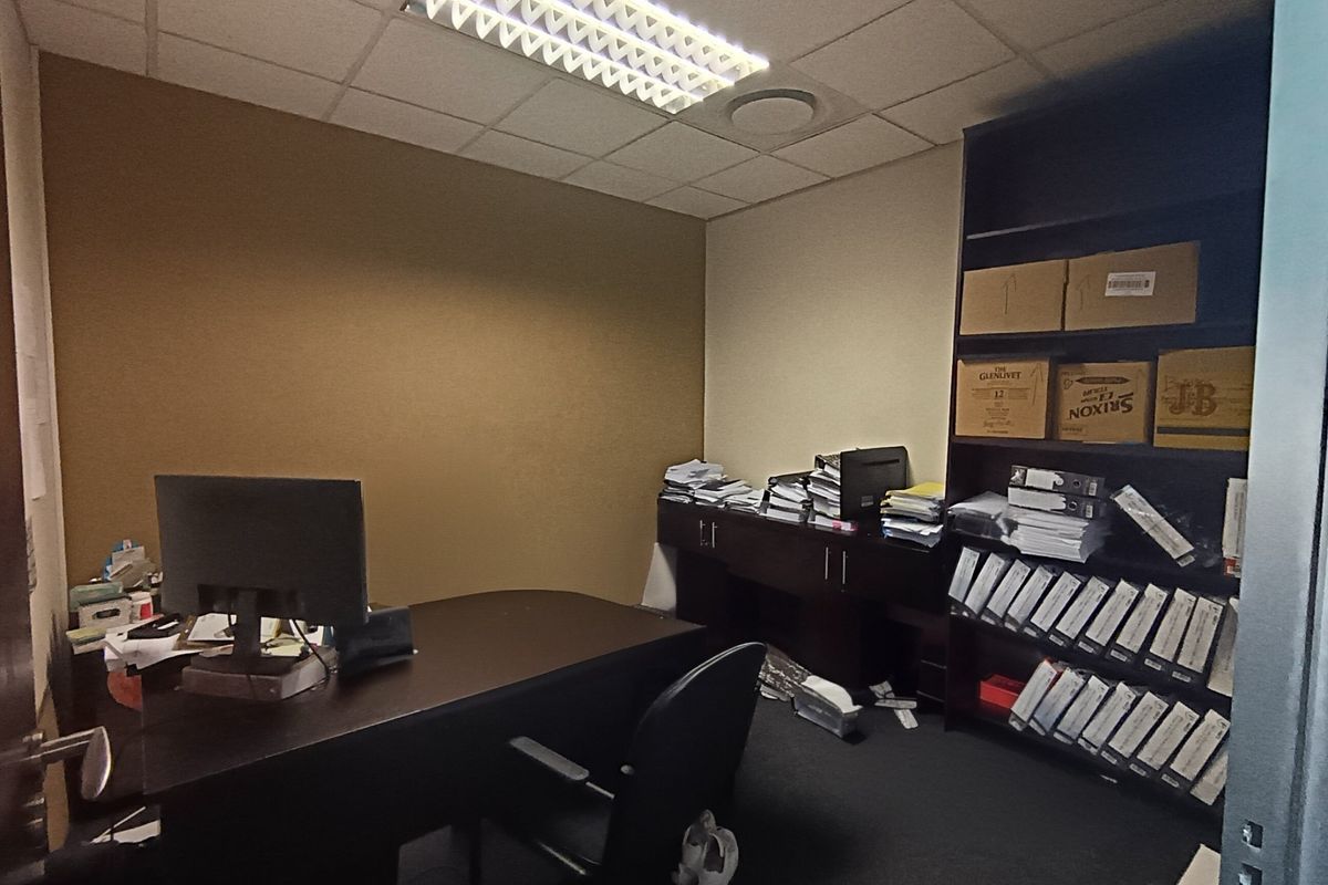 A functional office space featuring a suspended ceiling, integrated lighting, and built-in shelving, suitable for professional use.