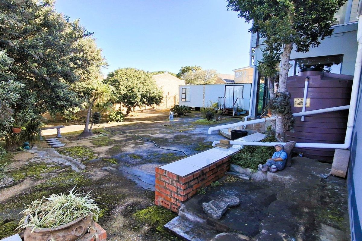 Rear garden area featuring concrete paving, a water storage tank, and a brick retaining wall, requiring maintenance and landscaping to improve curb appeal.