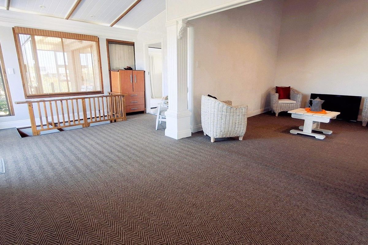Spacious living area featuring exposed beam ceilings, decorative columns, and large timber-framed windows, offering a bright and open atmosphere.