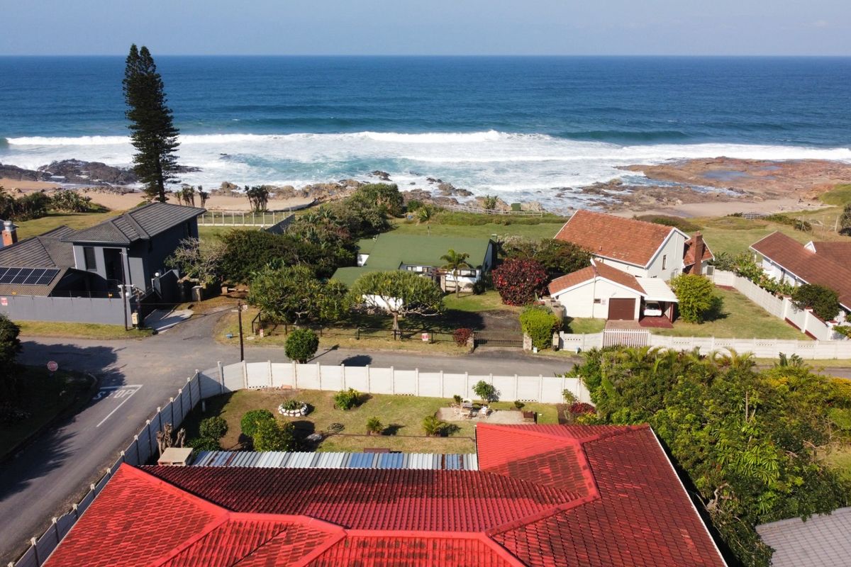 Aerial view of the coastal property showing the roof structure, surrounding neighborhood, and direct proximity to the oceanfront.