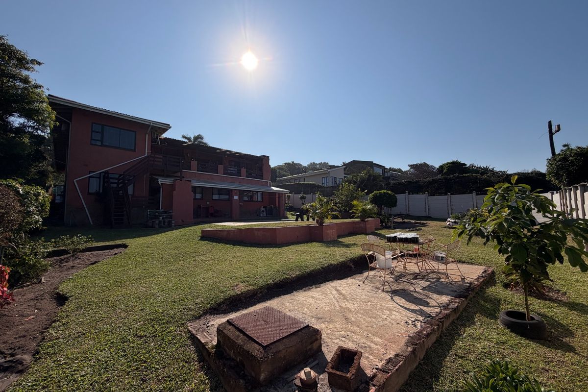 Rear view of the property featuring a large lawn, a raised patio area, and an external staircase leading to the upper level.