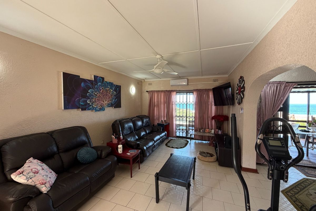 A living room featuring tiled flooring, a ceiling fan, and a split-system air conditioner, with an archway leading to an outdoor patio area.