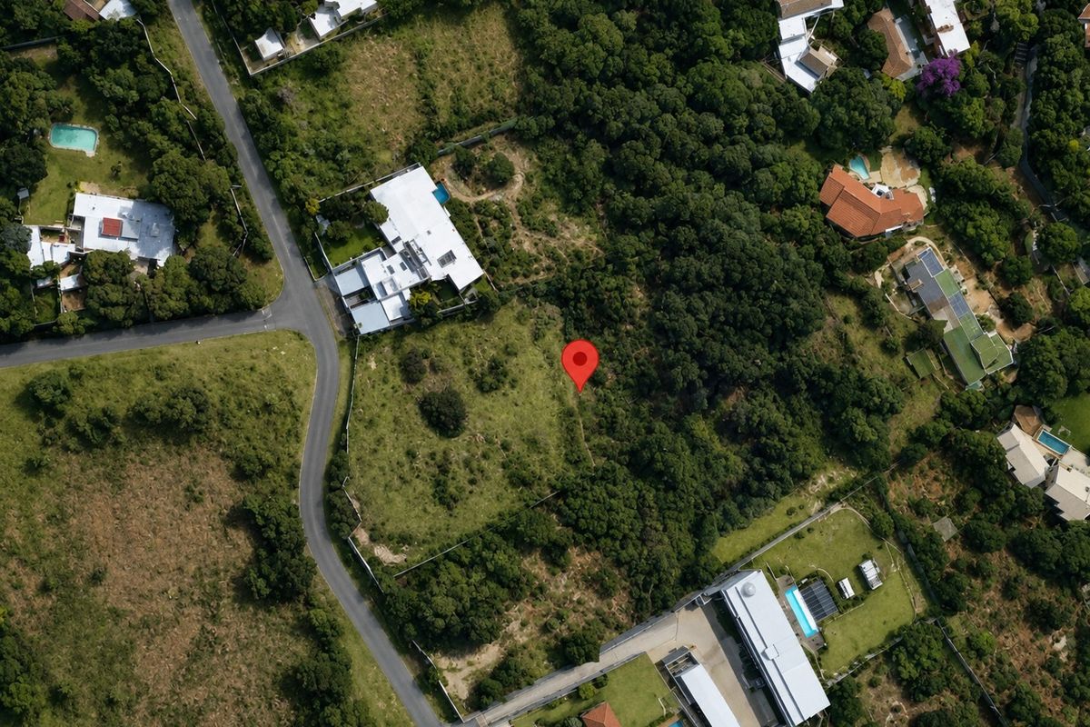 Aerial view of a vacant residential plot surrounded by established trees and neighboring properties in a suburban setting.