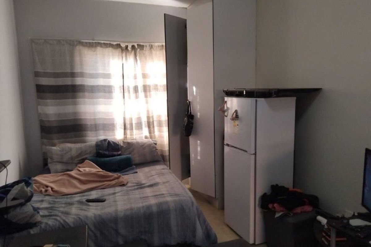 A compact bedroom featuring a built-in wardrobe and natural light from the window.