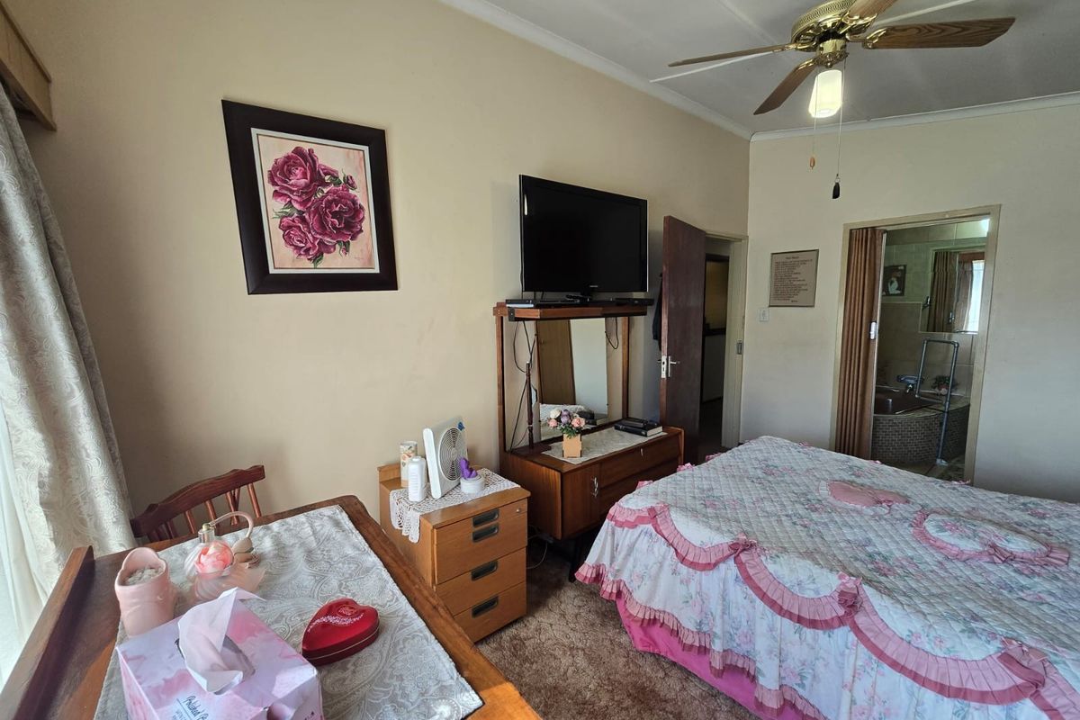 A bedroom featuring carpeted flooring, a ceiling fan, and direct access to an en-suite bathroom.