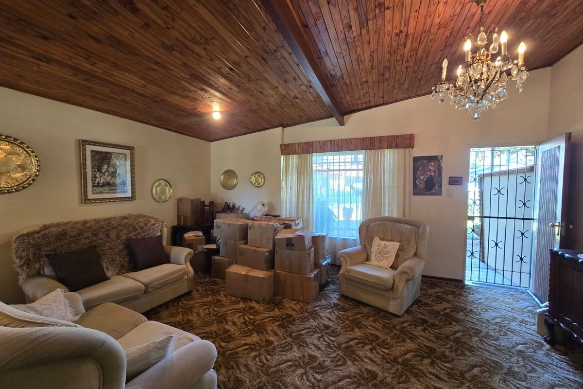Living room featuring a vaulted timber-clad ceiling, crystal chandelier, and direct access to the exterior via a security gate.