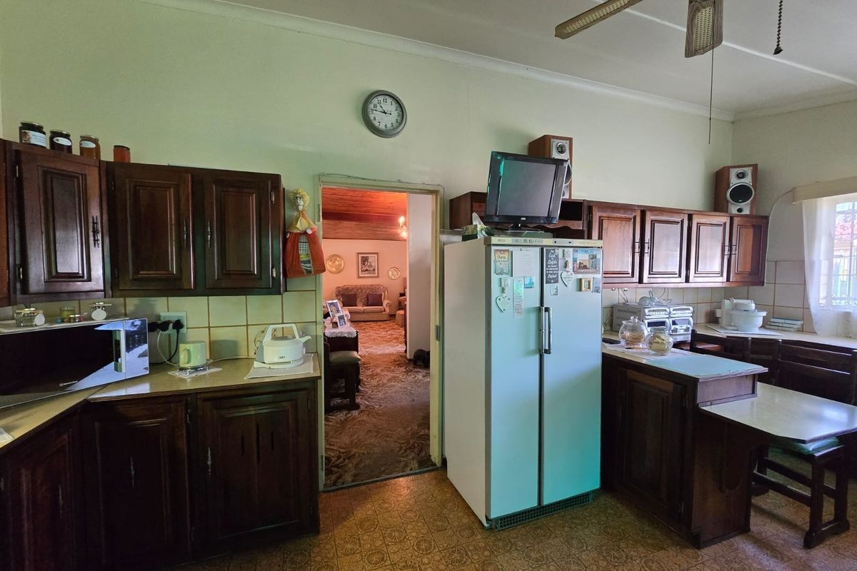A traditional kitchen featuring dark wood cabinetry, tiled backsplash, and a ceiling fan, offering a functional layout with potential for modern updates.