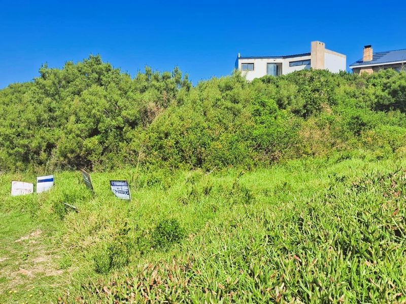A sloped residential vacant land plot featuring natural vegetation and surrounding neighborhood views.