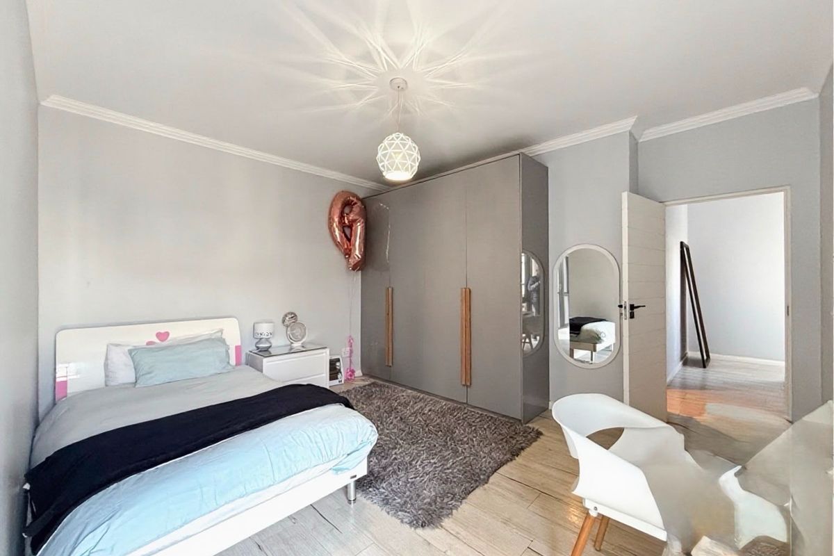 A well-maintained bedroom featuring light-toned flooring, a built-in wardrobe, and decorative ceiling cornice, offering a clean and functional living space.