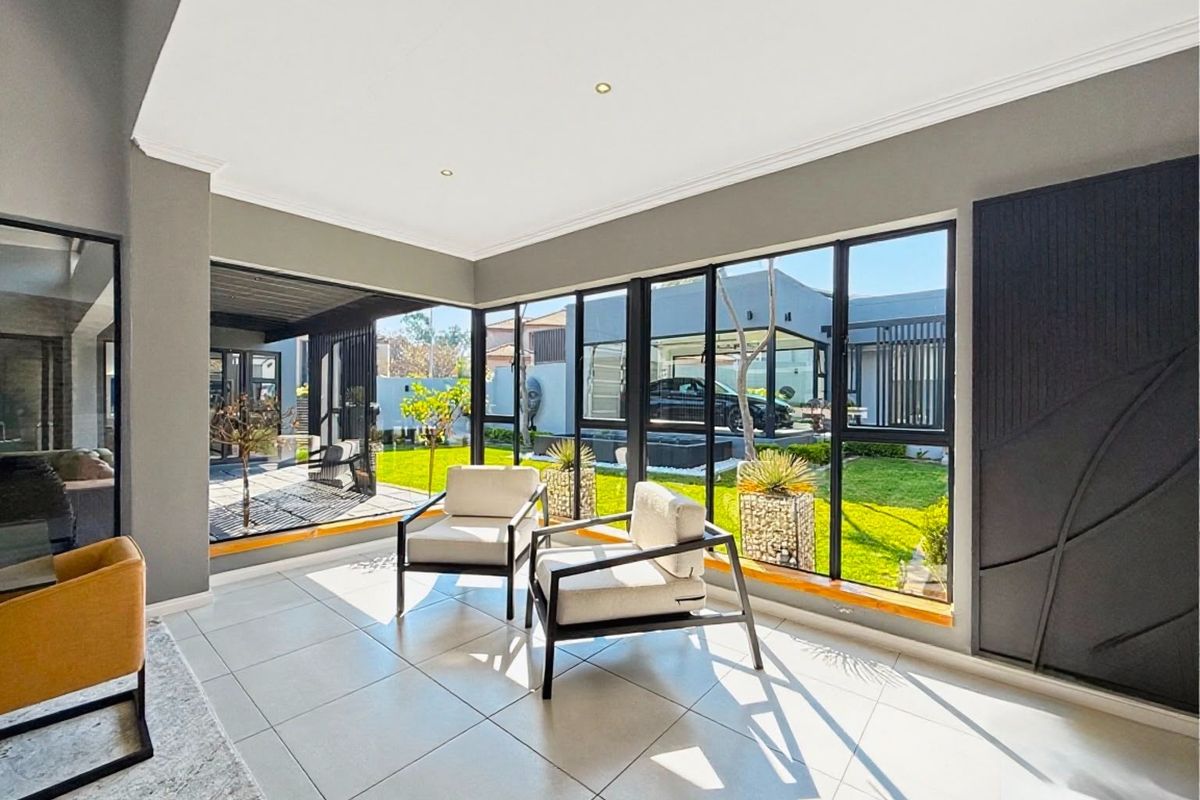 Bright and modern living area featuring large format floor tiles, extensive black aluminium framed windows, and direct access to the garden.