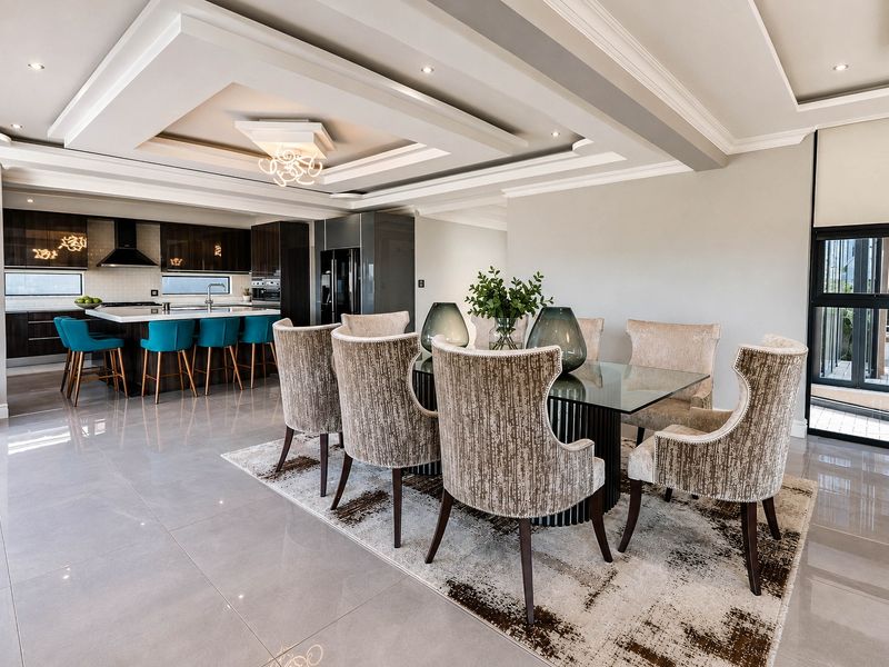 Spacious open-plan living area featuring a modern kitchen with island, recessed tray ceiling, and seamless flow to the dining space with tiled flooring.