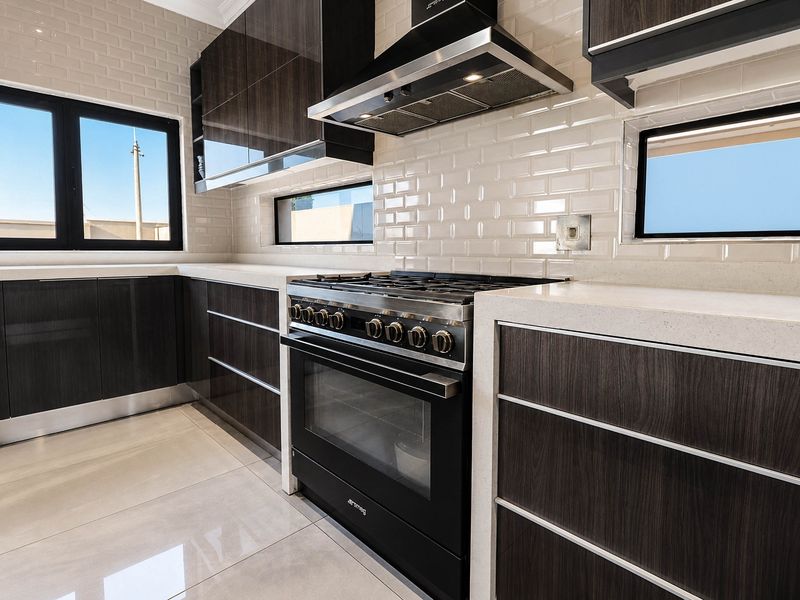Modern kitchen featuring dark wood cabinetry, stone countertops, subway tile backsplash, and a high-end Smeg gas range with integrated extractor fan.