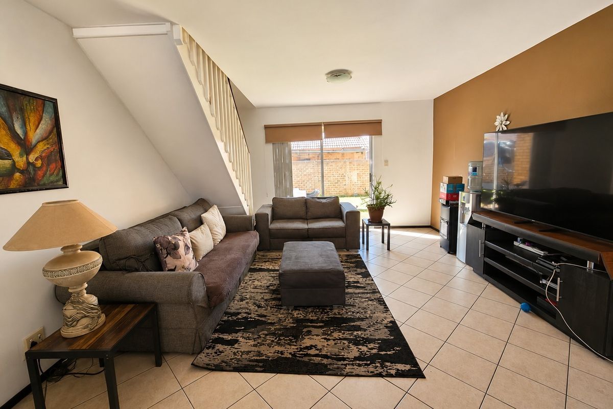 A living room featuring tiled flooring, a staircase with a balustrade, and a sliding glass door providing access to the rear exterior.