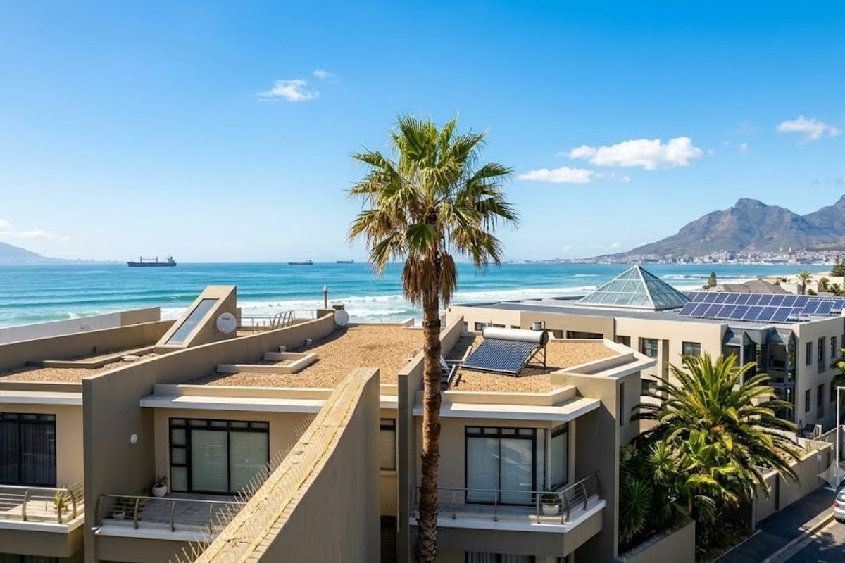 Aerial view of a modern residential complex featuring solar panels, skylights, and balconies with scenic ocean and mountain views.