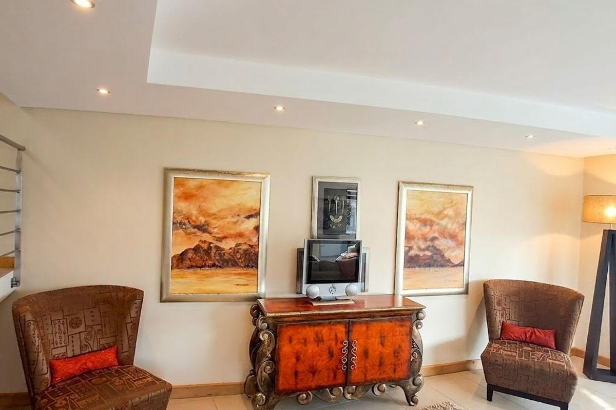 A well-maintained living area featuring neutral tiled flooring, recessed ceiling downlights, and clean wall finishes.