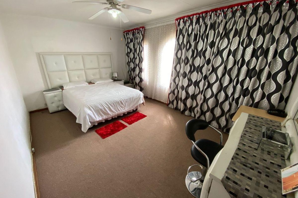 A spacious bedroom featuring carpeted flooring and a ceiling fan, offering a comfortable layout with ample natural light.
