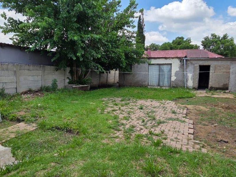 Rear garden area featuring a paved patio, precast concrete boundary walls, and access to the main dwelling via a sliding glass door.