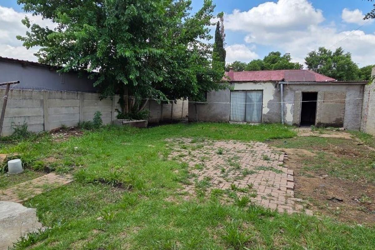 Rear garden area featuring a paved patio, precast concrete boundary walls, and access to the main dwelling via a sliding glass door.