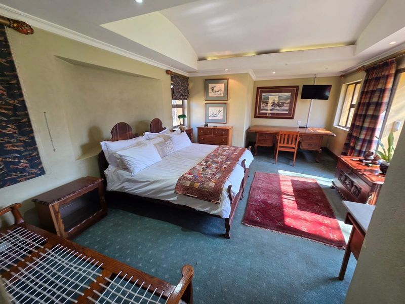 Spacious bedroom featuring a tray ceiling with recessed lighting and a built-in desk area, offering a comfortable and functional living space.