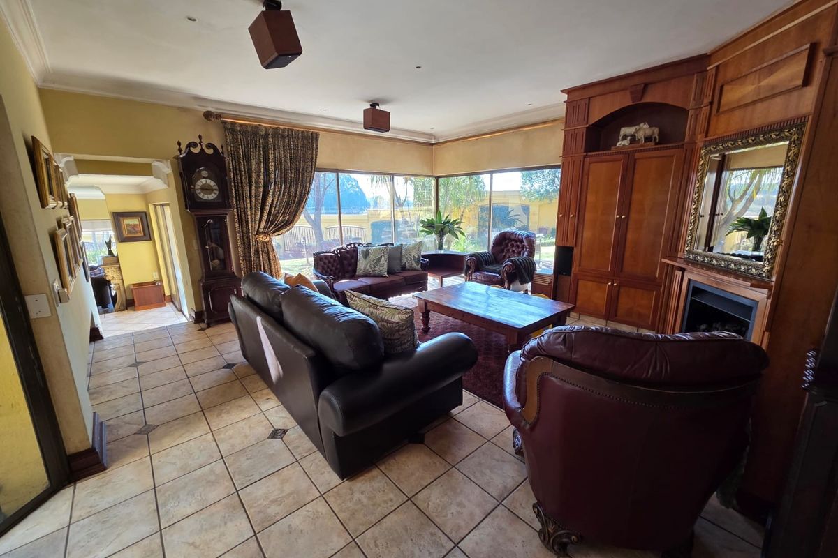 Spacious living room featuring tiled flooring, built-in wooden cabinetry, a fireplace, and large glass sliding doors providing natural light and garden views.