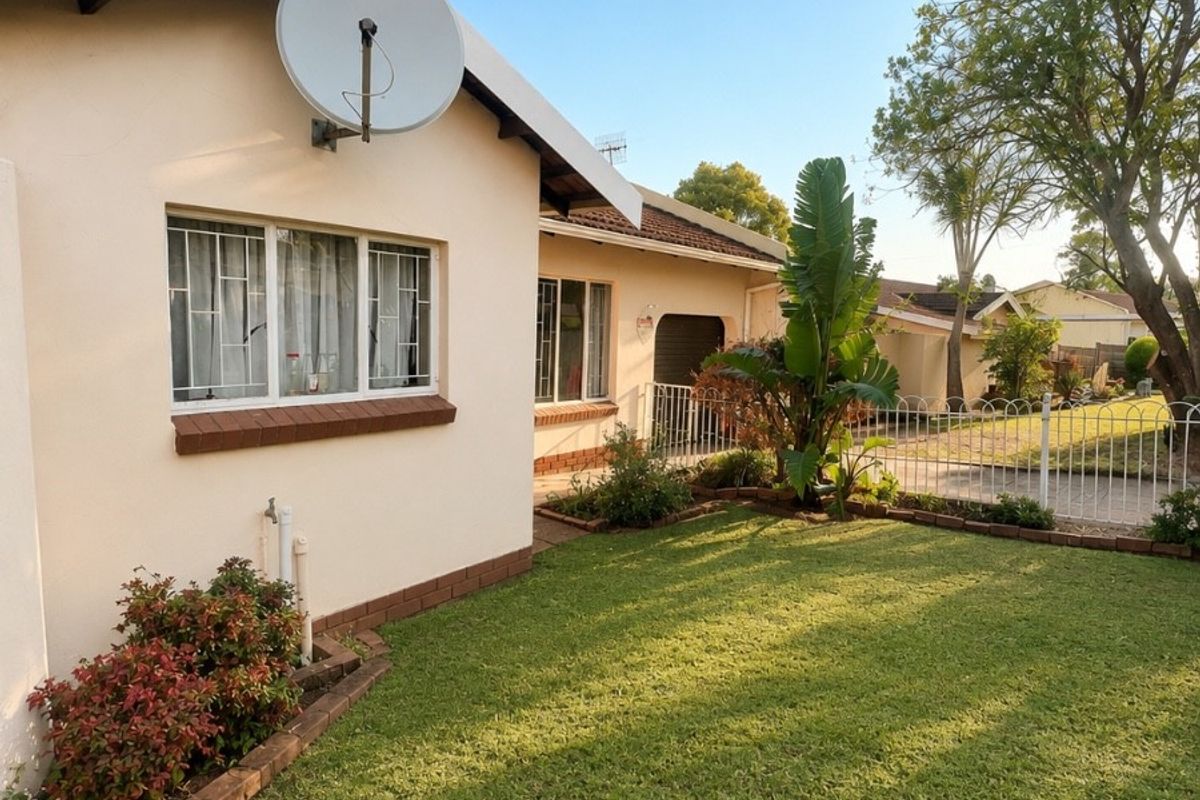 A well-maintained rear garden area featuring a lawn, established landscaping, and secure perimeter fencing, attached to the townhouse exterior.