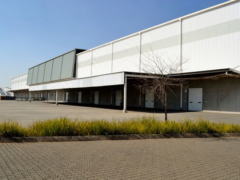 Industrial warehouse facility featuring multiple loading bay doors, extensive concrete hardstand area, and modern corrugated metal cladding.