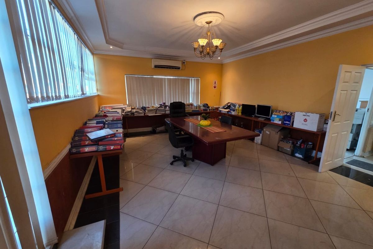 Spacious office area featuring tiled flooring, split-system air conditioning, and large windows with vertical blinds, offering a functional workspace environment.