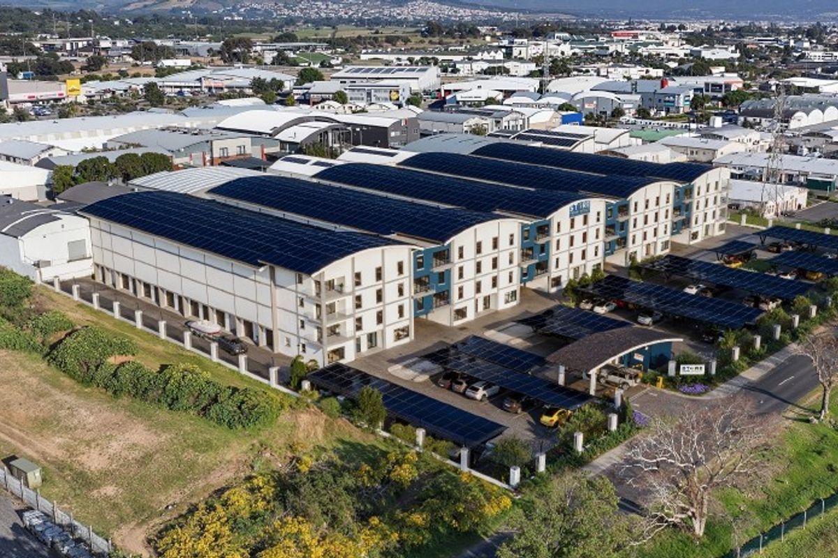 Aerial view of a modern commercial property complex featuring extensive rooftop solar installations and covered parking facilities within an industrial business park.