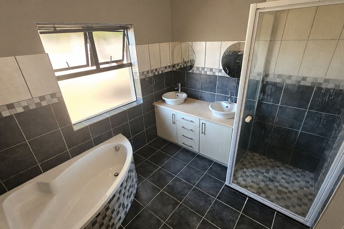 A spacious bathroom featuring a freestanding bathtub, a separate shower enclosure, and a double vanity with vessel sinks and tiled finishes.