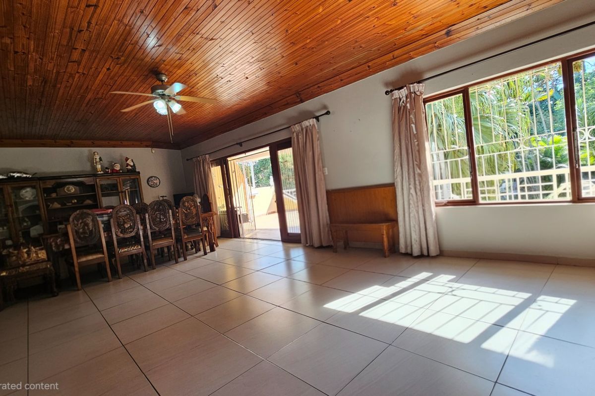 Spacious living area featuring a warm timber-clad ceiling, large tiled floors, and sliding glass doors that provide access to the outdoor space.