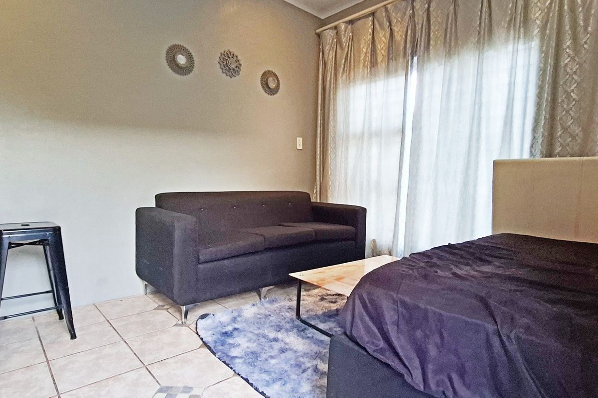 A bedroom featuring tiled flooring, a sliding glass door with curtains, and a built-in wall shelf, offering a functional living space.