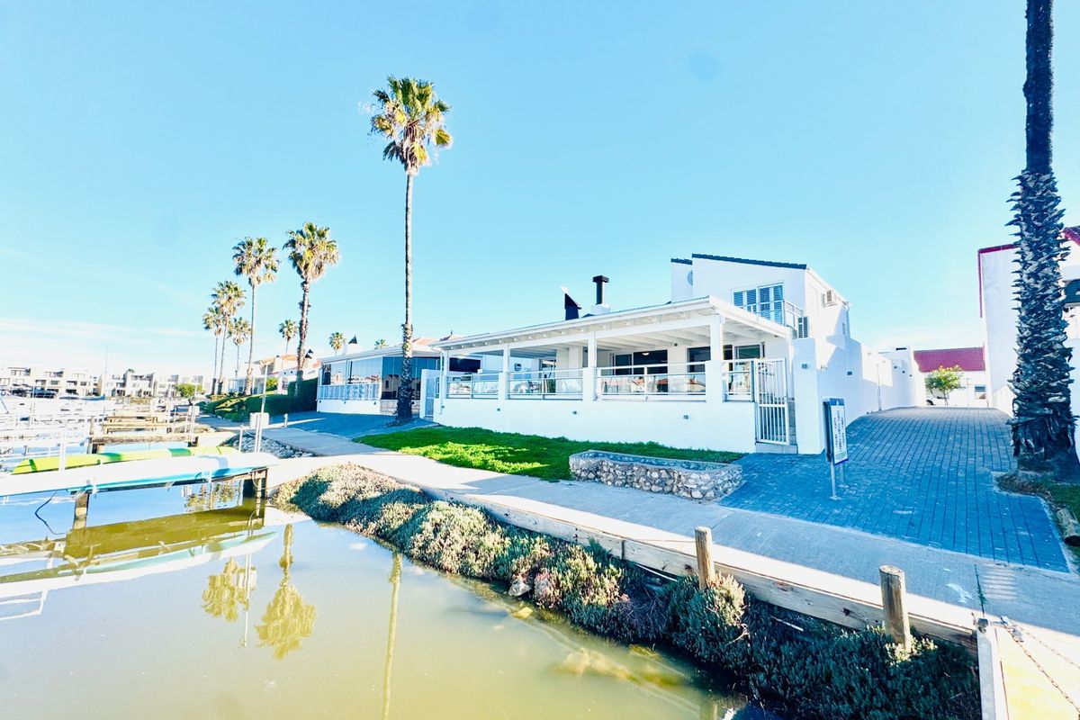 A well-maintained waterfront property featuring a covered patio, paved driveway, and direct access to the canal with a private jetty.