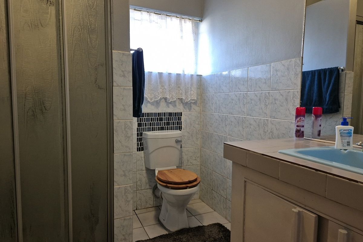A functional bathroom featuring a shower enclosure, a vanity cabinet with a basin, and tiled wall finishes.