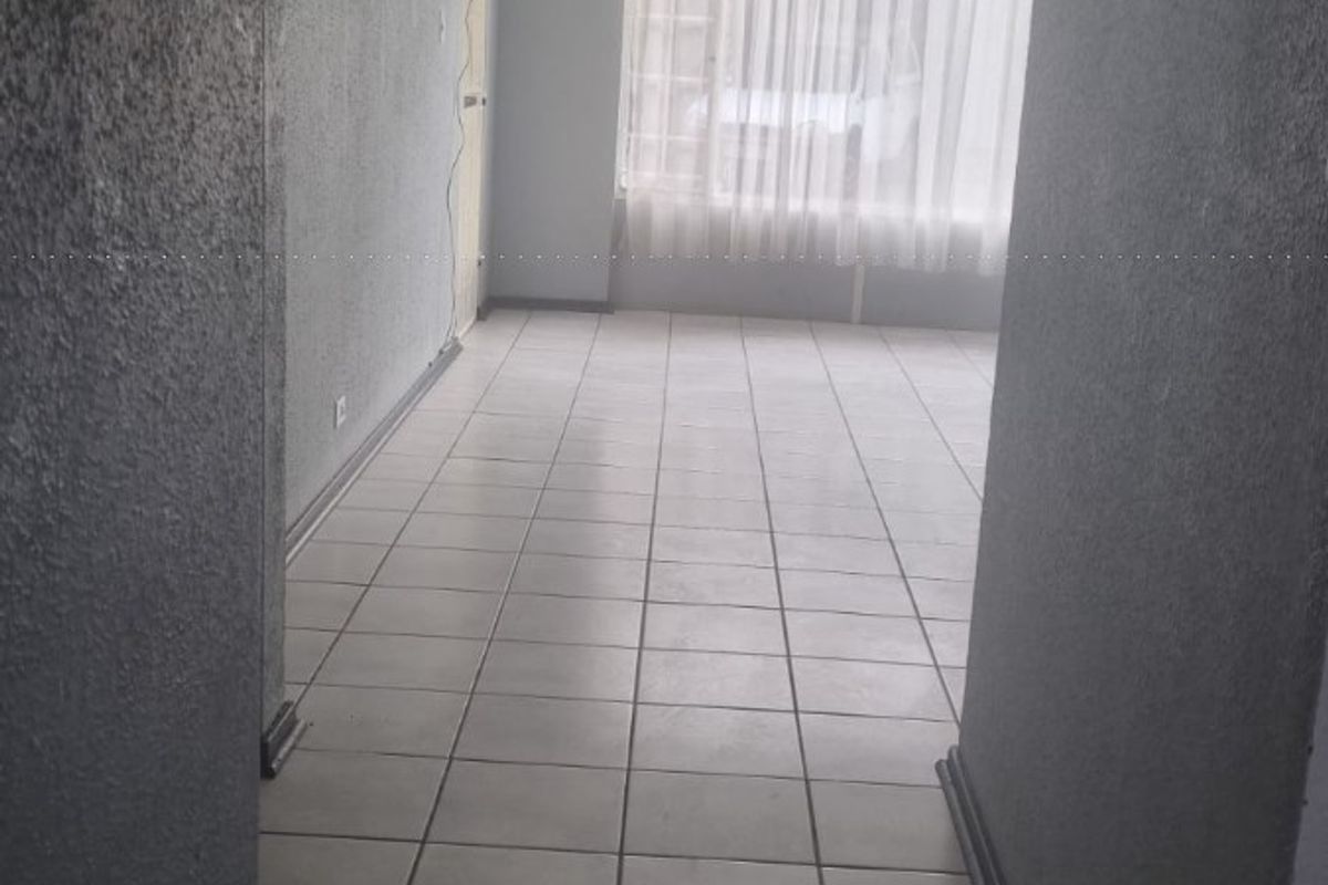 An empty, open-plan living area featuring neutral tiled flooring and textured walls, offering a blank canvas for interior design.