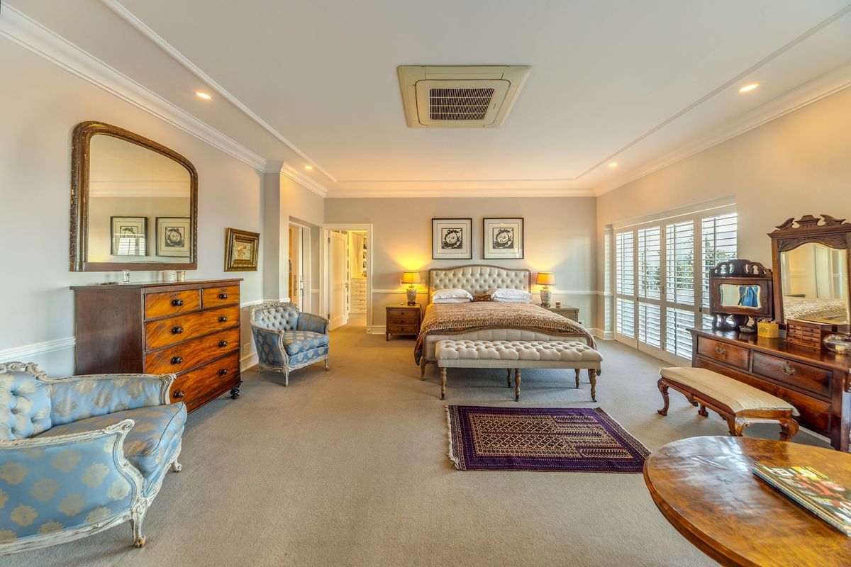 Spacious master bedroom featuring crown molding, ceiling-mounted air conditioning, and plantation shutters, offering a bright and well-maintained living space.
