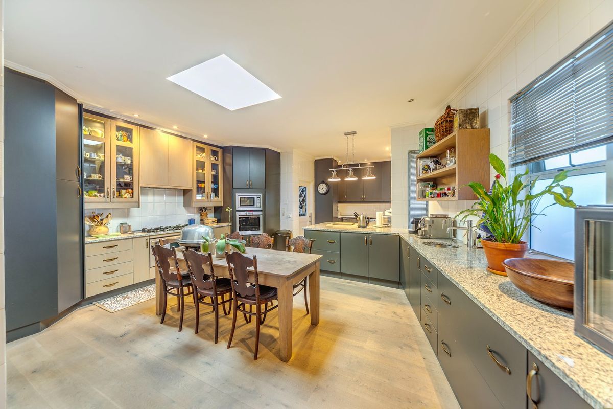Spacious modern kitchen featuring granite countertops, integrated appliances, ample cabinetry, and a large central skylight providing abundant natural light.