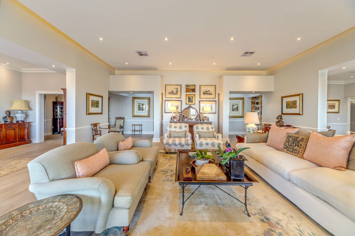 Spacious living room featuring recessed downlighting, cove lighting, and elegant chair rail molding, finished with high-quality hardwood flooring.