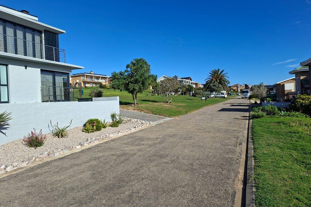 A clear street view showing the asphalt road, concrete curbing, and landscaped verges in a residential neighborhood setting.