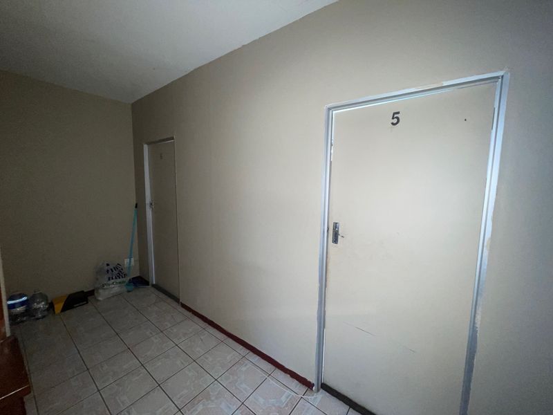 A simple, tiled hallway featuring neutral walls and multiple doorways, providing access to various rooms within the apartment.