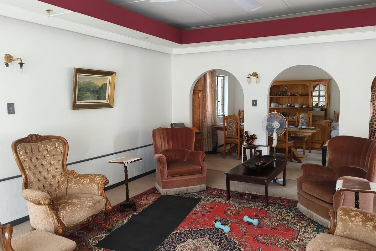 A spacious living room featuring distinctive architectural archways leading to an adjacent dining area, complemented by a coved ceiling and wall-mounted lighting fixtures.