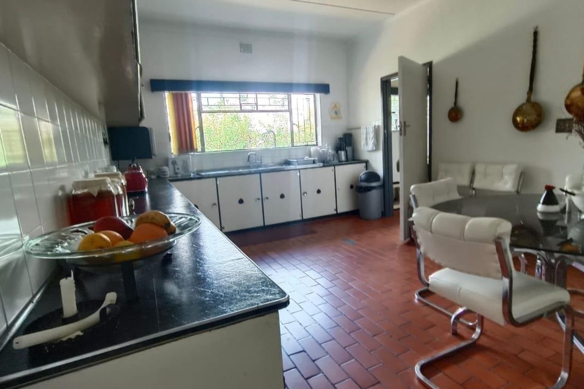 A functional kitchen featuring dated cabinetry, laminate countertops, and traditional terracotta floor tiles, offering potential for a modern renovation.