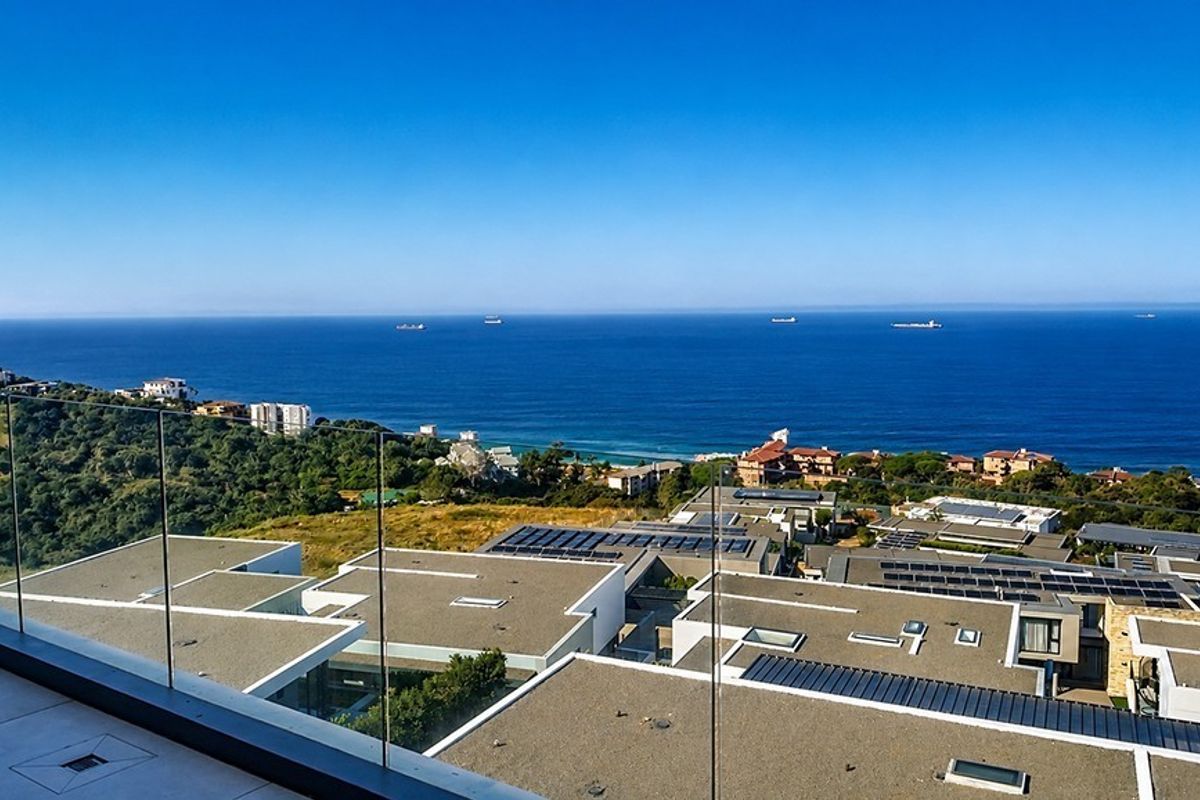 Elevated balcony view overlooking the coastline and surrounding residential estate with clear ocean horizon.